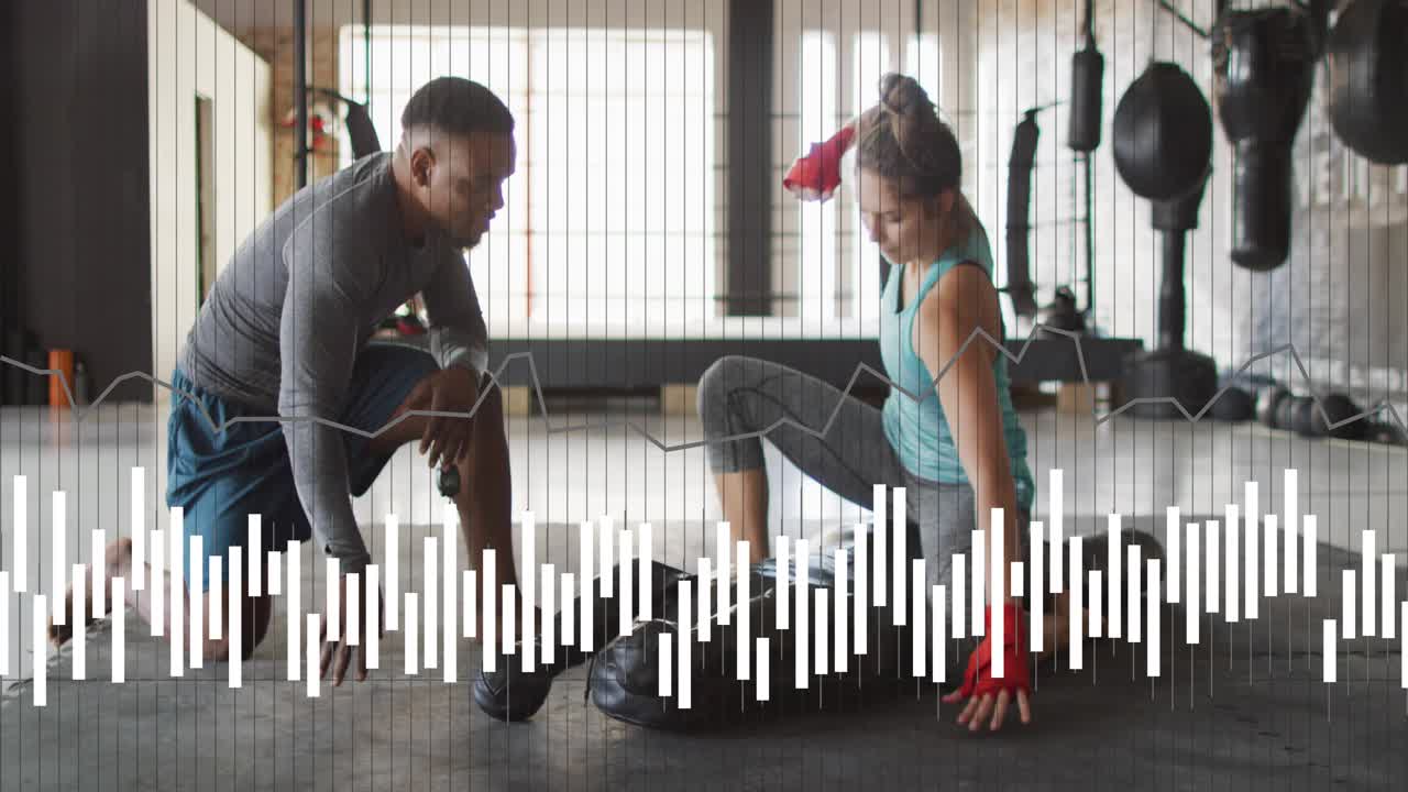 Coach gesturing leading trainee fixing red wraps preparing bag for boxing with sound bar over mat