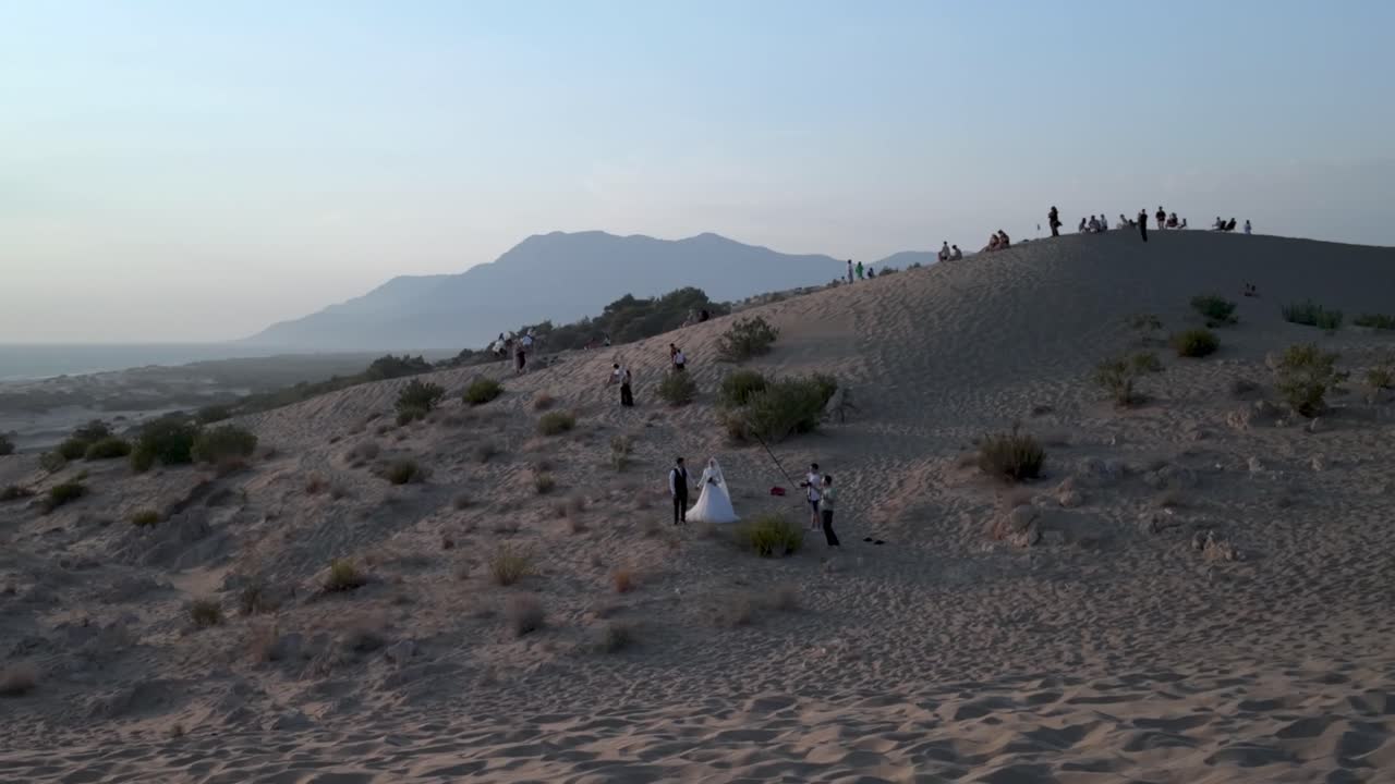 Couple takes wedding photos on sand dunes by the sea
