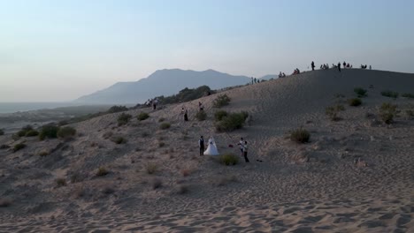 couple takes wedding photos on sand dunes by the sea