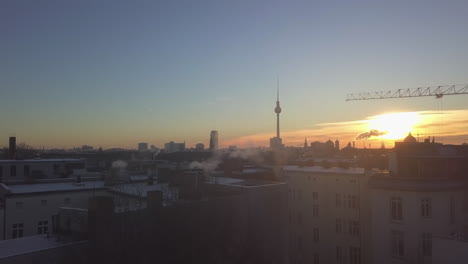 Rising-up-flight-behind-house-or-Apartment-Buildings-in-Berlin,-Germany-revealing-beautiful-morning-light-in-Winter,-Aerial-Shot