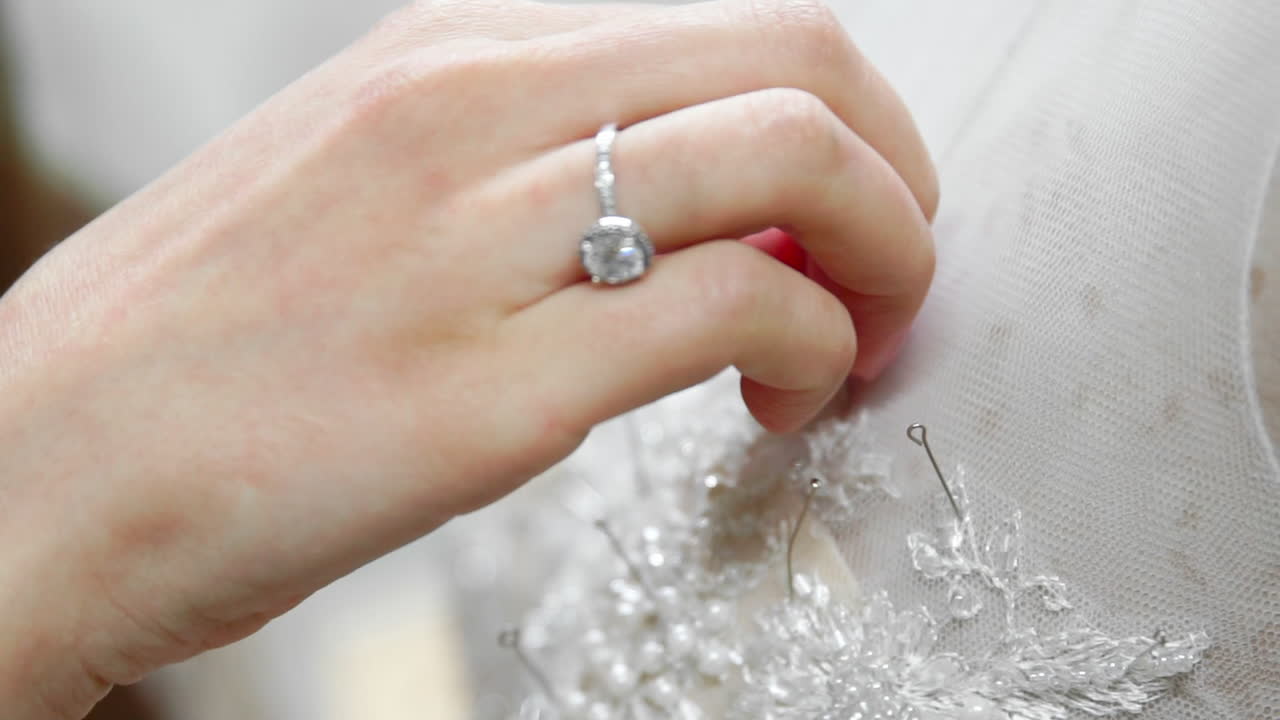 Close-up fashion designer for brides in his Studio pins needles lace wedding dress. Seamstress creates an exclusive wedding dress. Secure with pins and needles outline. Small private business