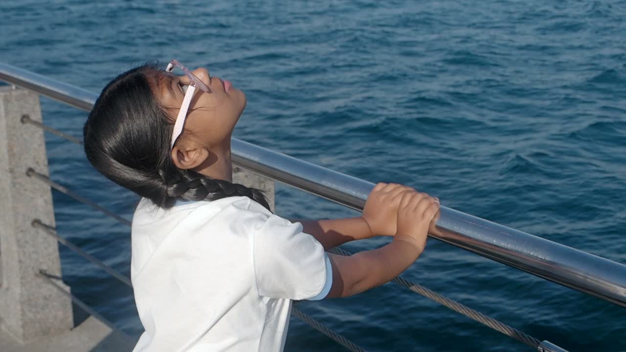 Young girl looking out at the ocean from a railing