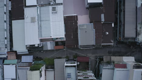 top down drone shot flying low over rooftops and alleyways in urban residential area of major city in south east asia