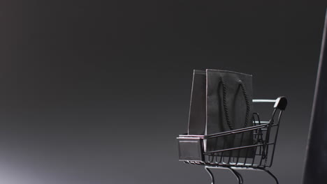 video de portátil con pantalla en blanco, bolsa de compras y carrito con espacio de copia sobre fondo blanco