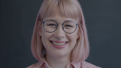 smiling woman with pink hair and glasses