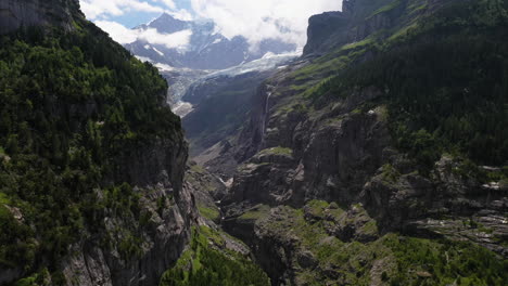 Drone-shot-of-mountains-near-Grindelwald,-in-Switzerland’s-Bernese-Alps,-with-a-waterfall-in-the-distance