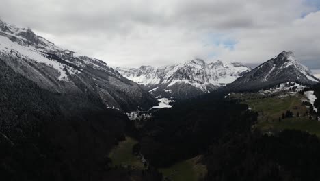 A-grand-panorama-of-the-Swiss-Alps-reveals-snow-draped-peaks-under-a-veil-of-clouds-and-mist,-situated-near-Glarus,-Switzerland