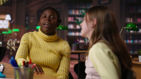 dos chicas hablando en una biblioteca