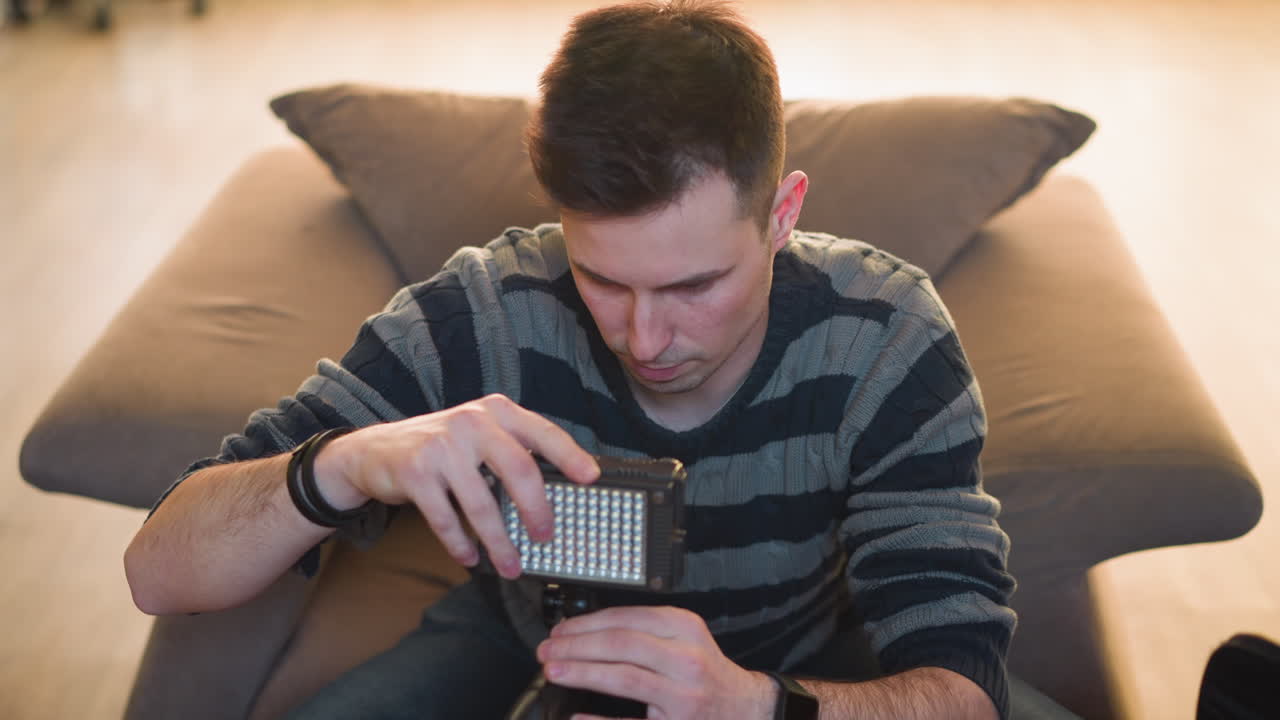 Person reaching for equipment bag on table while sitting on couch. Focus on hand extending to grab item. Indoor setting with soft light and a relaxed, comfortable atmosphere