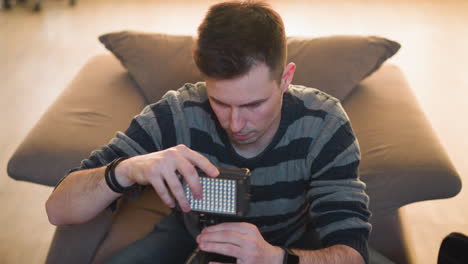 person reaching for equipment bag on table while sitting on couch. focus on hand extending to grab item. indoor setting with soft light and a relaxed, comfortable atmosphere