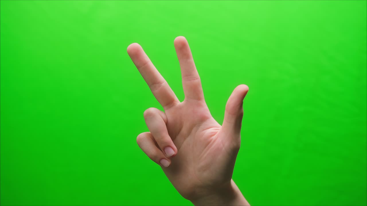 Close-up of a hand gesture on a green background, three raised fingers, shooting a gesturing in studio