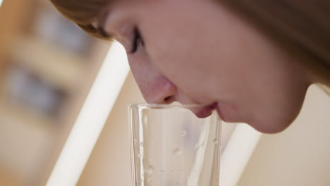 woman with closed eyes enjoys drinking water from glass