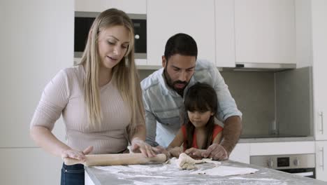 little girl and her dad baking while mom rolling dough