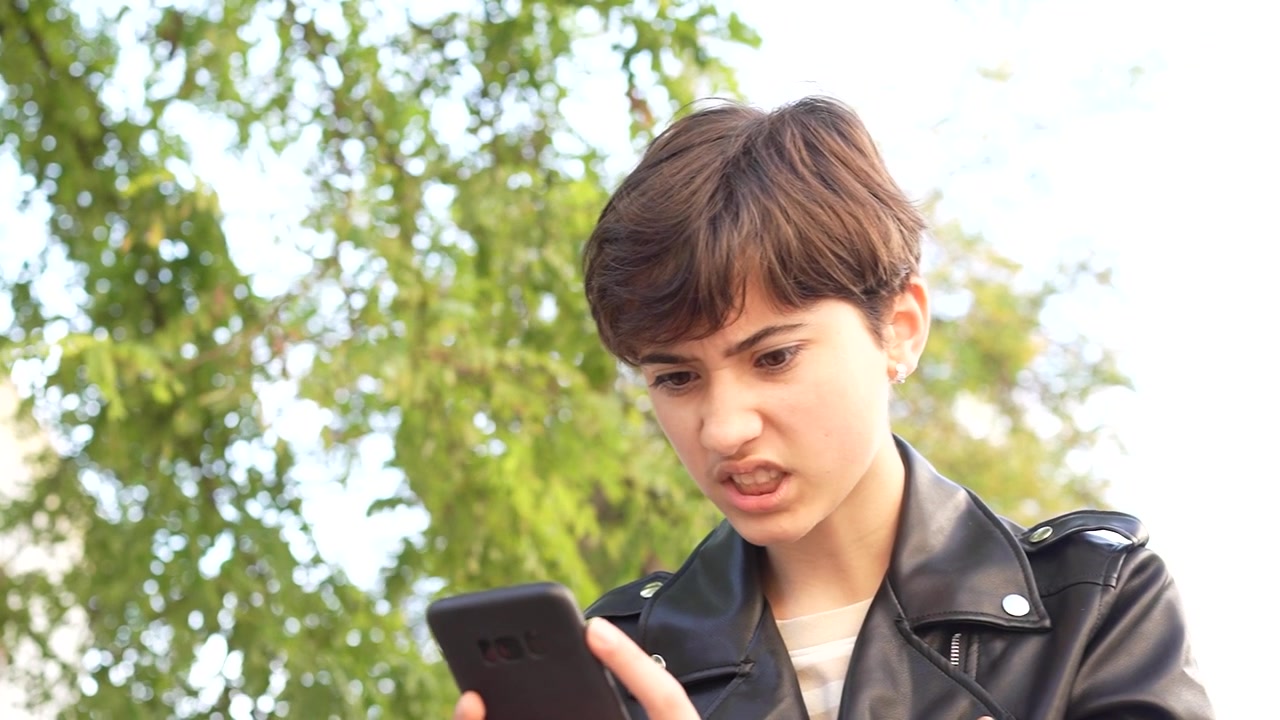 Una persona giovane assorta nel suo smartphone mentre svolge attività urbane in città.