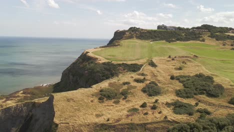 aerial drone shot of coastline with ravenscar with green fields and ocean