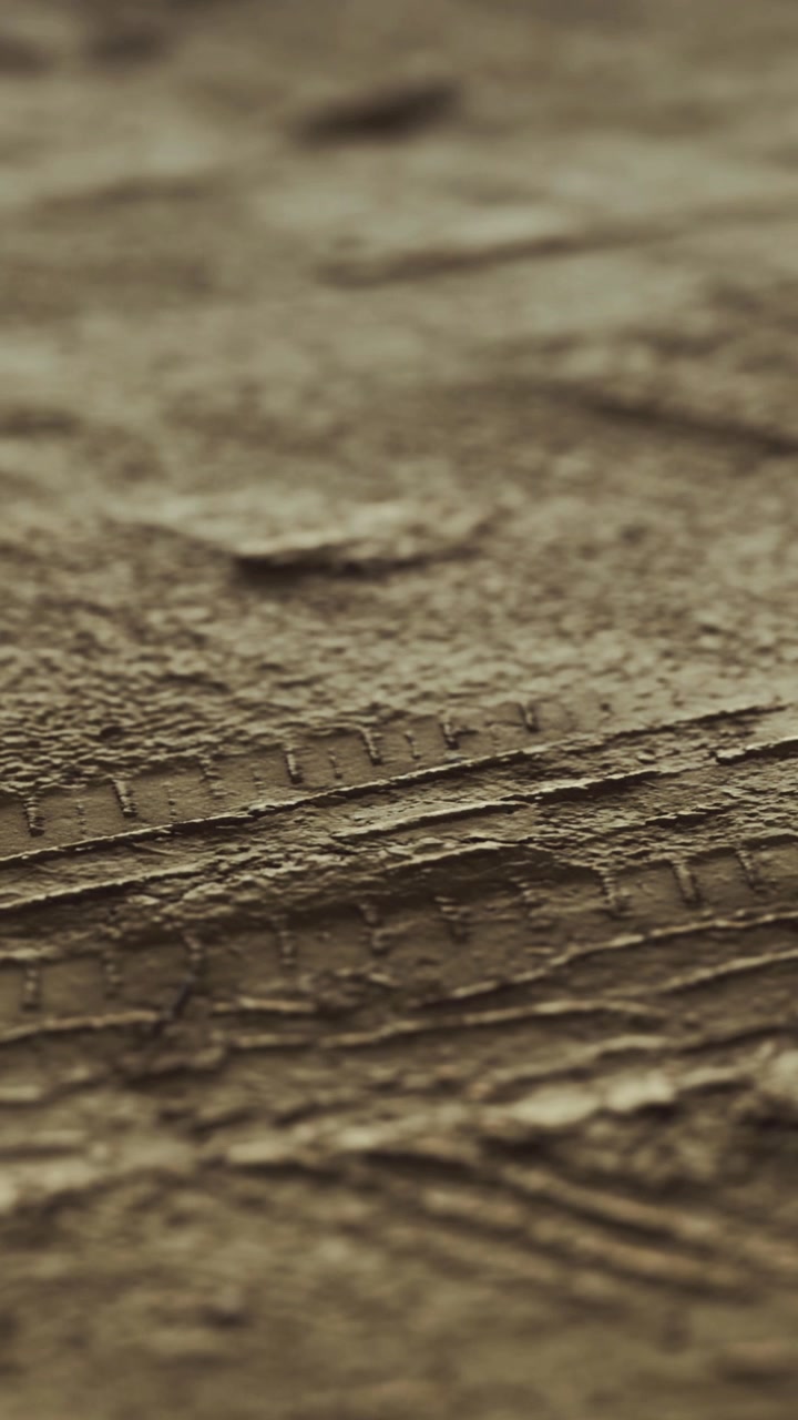 Detailní pohled na texturovaný povrch ukazující vzory a linie v tlumených barvách.