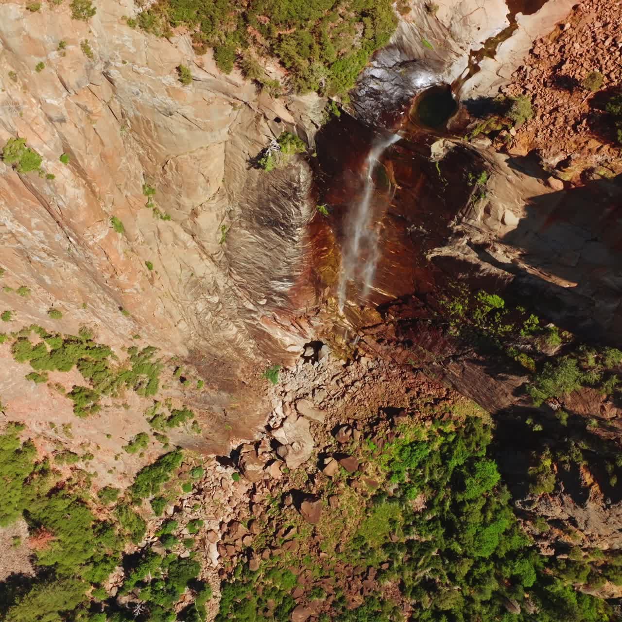 Tiny creek falling from steep cliff in Yosemite National Park, California, USA. Almost dried waterfall from aerial view on sunny hot day