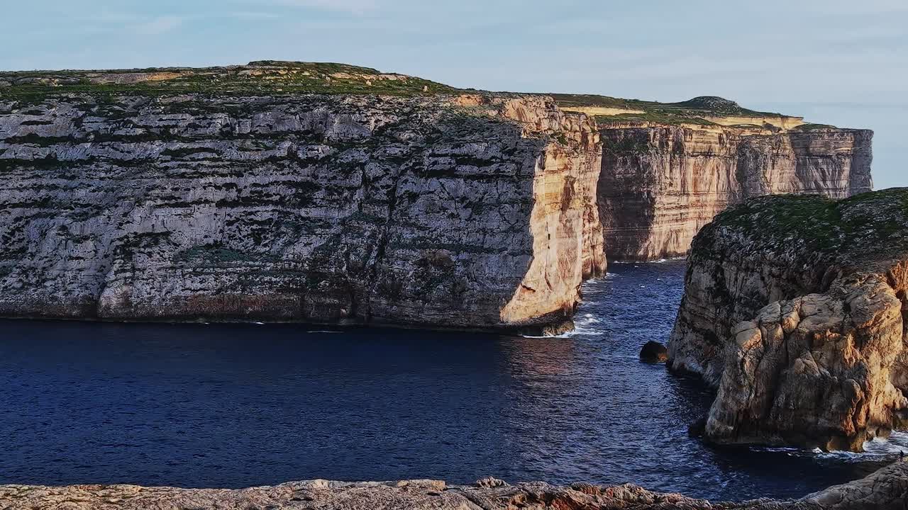 Coastal cliffs in Malta with clear sky and calm waters during sunset