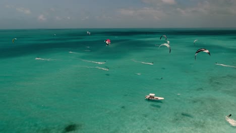 MANY-COLORFUL-KITES-FLY-AROUND-CARIBBEAN-SEA,-DRONE-SHOT-lOS-ROQUES-VENEZUELA