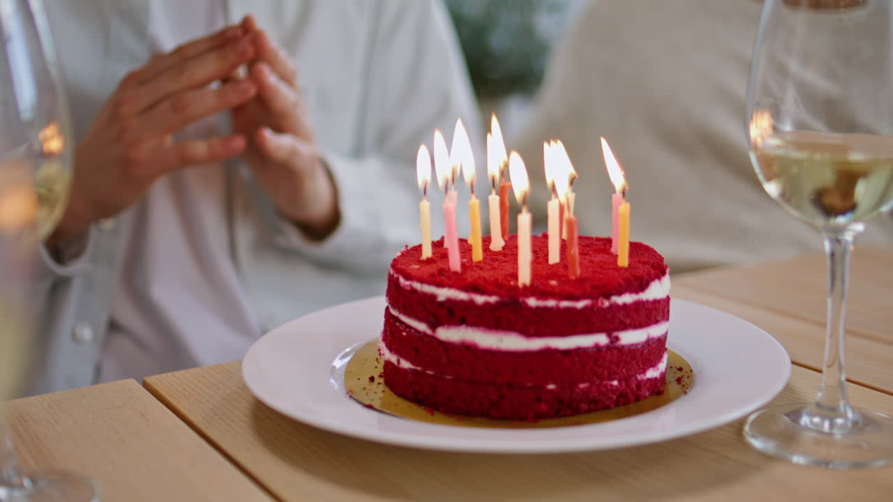 Birthday boy blowing cake burning candles home party closeup. People celebrating