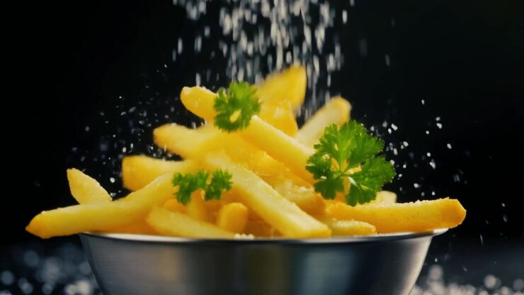 French Fries Falling into a Metal Bowl with Salt and Parsley