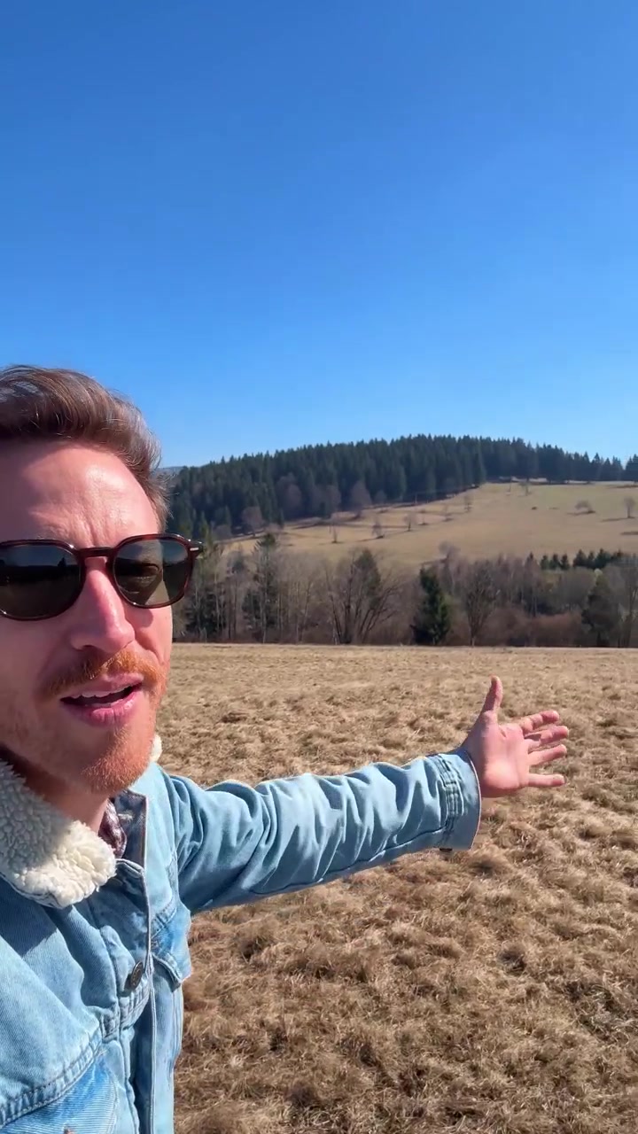 Content creator or influencer making a vid. Vertical selfie-style footage of a male travel influencer walking through an open mountain landscape on a sunny day. UGC content traveling vlogger. reel