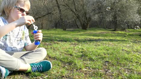 little young boy playing with soap bubbles during sunny day.