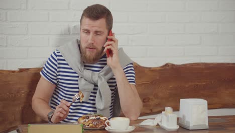 man eating and talking on phone in a cafe