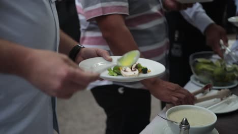 slow motion shot of a group of people dressing their plates of food with a garnish