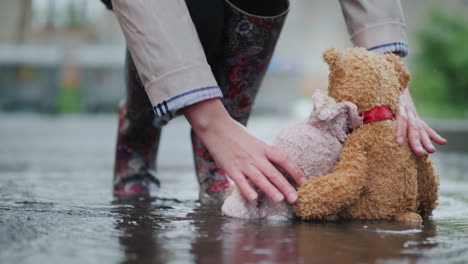 a man raises two wet toys from a puddle help and hope concept lost toys 4k video