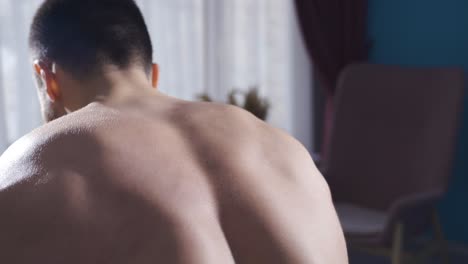 젊은 보디빌더 남자가 허리를 위해 덤벨을 사용하여 근육을 운동합니다.