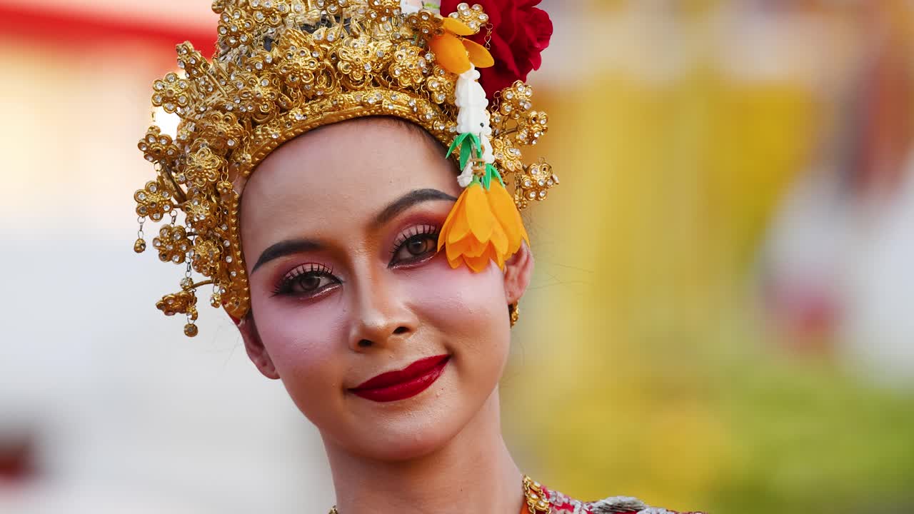 Cận cảnh một vũ công Thái Lan đang mỉm cười khi đội chiếc mũ chadat vàng trang trí công phu.
