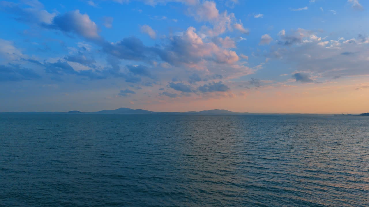 Tramonto sull'acqua e nuvole nel cielo. Le onde incontrano l'orizzonte mentre la luce del sole si affievolisce e le nuvole fluttuano sull'acqua. Il giorno si trasforma in sera in questa vista serena