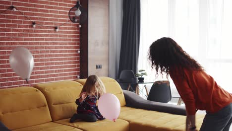 mamá rizada y su encantadora hija jugando juntos con globos rosados