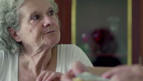 Cheerful-elderly-woman-having-breakfast-at-kitchen.