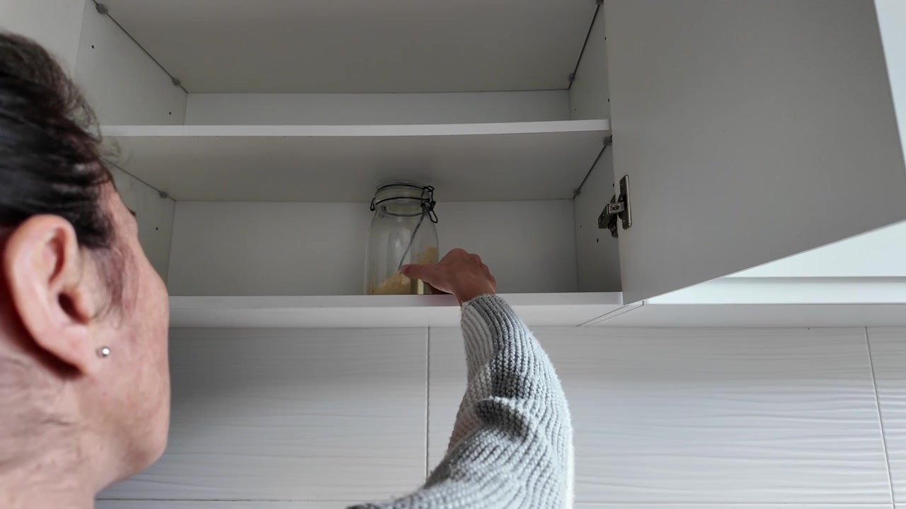 Woman opening almost empty pantry, food shortage and inflation concept