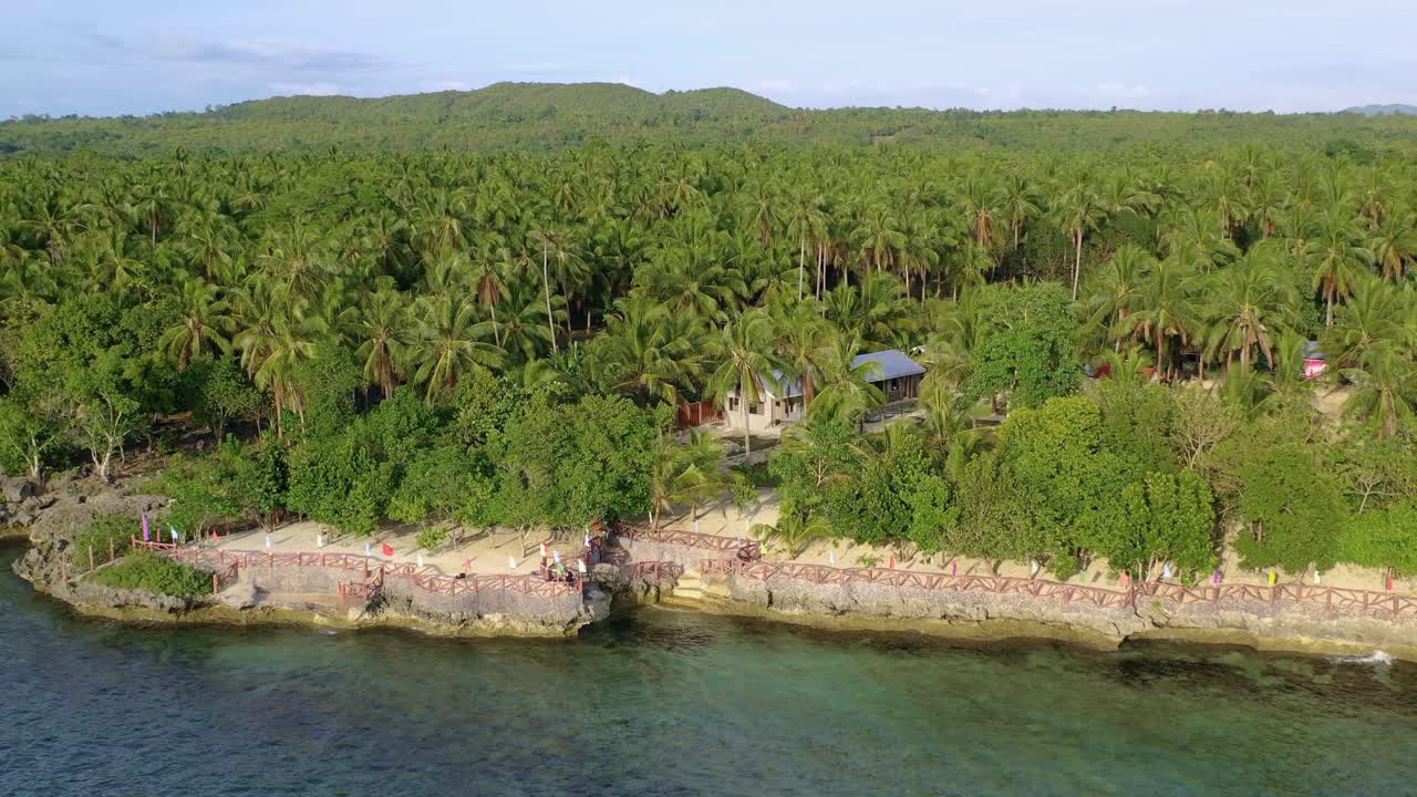 Pristine tropical forest, clear water and villas by the seashore, Philippines