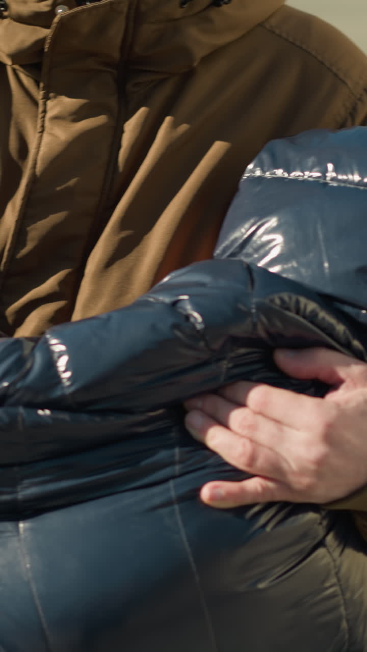 위에서 아래로 보이는 아버지가 는 동안 잠자는 아이를 들고, 스트레스를 받고, 아버지는 갈색 재과 베니를 입고, 아이는 검은색 재을 입고 있습니다.