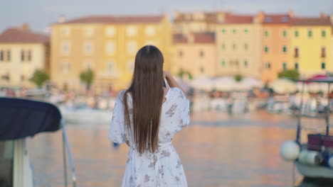 woman taking pictures of a croatian harbor town at sunset