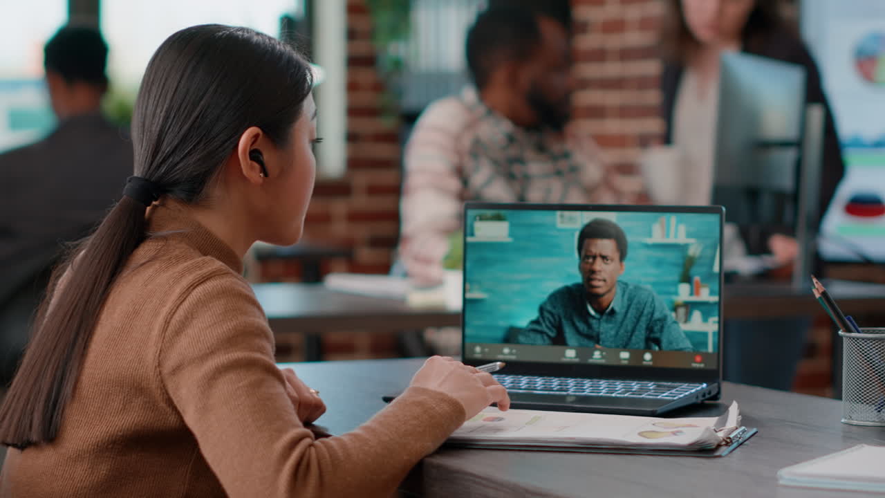 Asian woman attending online videocall meeting on laptop