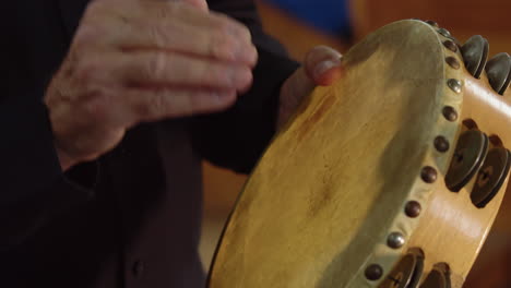 hombre de cerca tocando el instrumento de percusión de pandereta en orquesta