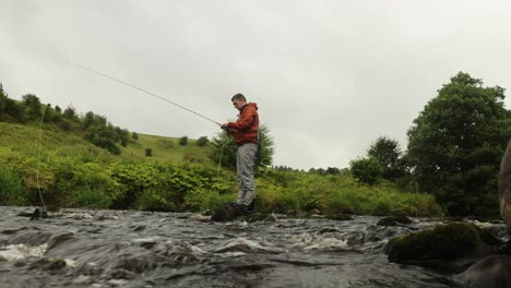 Toma-De-ángulo-Bajo-De-Un-Pescador-Con-Mosca-Revisando-Sus-Señuelos-En-Su-Línea.