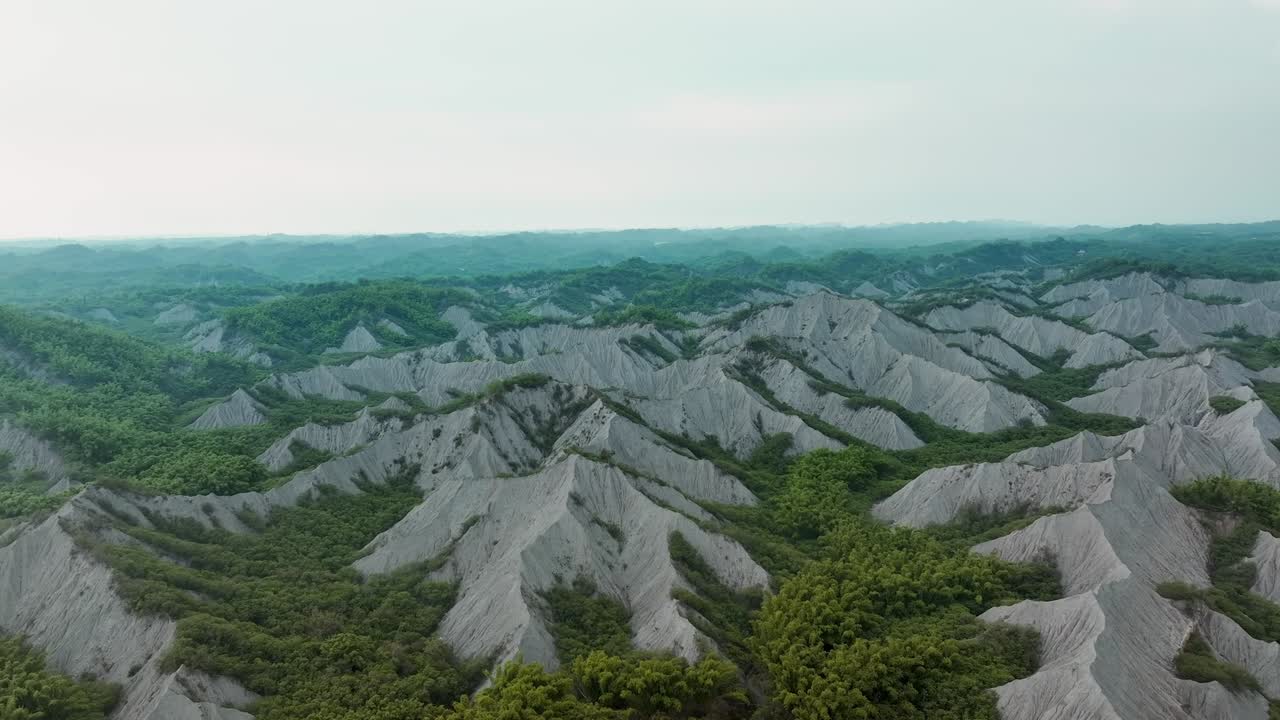 Aerial establishing shot above Tianliao Moon World during sunny day in Taiwan - Moonscape landscape after historic stream erosion - Taiwan, Kaohsiung
