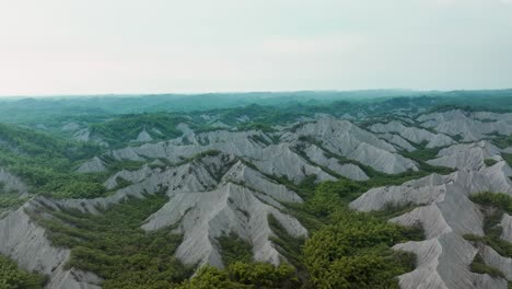 aerial establishing shot above tianliao moon world during sunny day in taiwan - moonscape landscape after historic stream erosion - taiwan, kaohsiung