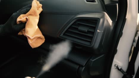 male wearing black gloves cleaning a dashboard side air vent with steam