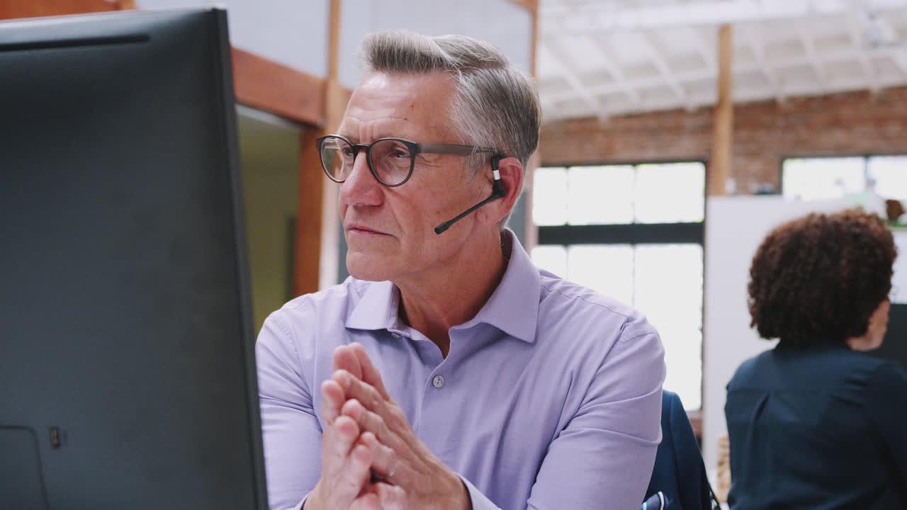 agente de servicios al cliente de sexo masculino maduro trabajando en el escritorio en un centro de llamadas