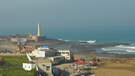 Lighthouse-on-the-shore-with-surf-waves-crashing-into-the-rocks-at-the-Rabat,-Morocco-shoreline---slow-motion