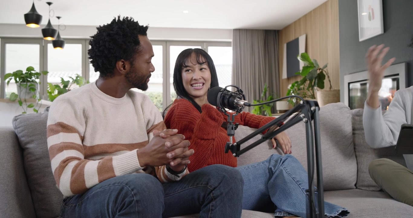 African American hosts sitting sofa in living room holding tablet host sparking chat mics recording