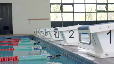 starting blocks line up at an indoor swimming pool, ready for a race