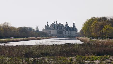 chambord castle view with canal, spring trees, tourists, peaceful and historic vibe